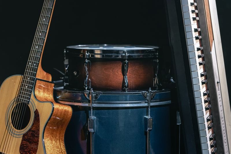 Acoustic guitar, drums and keys on a black background.